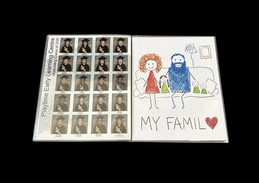 Open book spread showing the graduating class photo sheet opposite the child's own family drawing