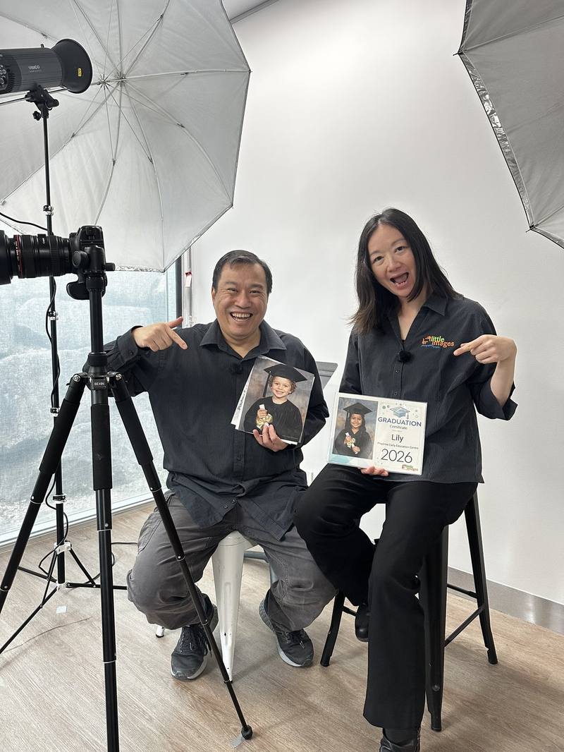 Hetty and David in their studio, holding graduation keepsake portraits and a personalised graduation certificate